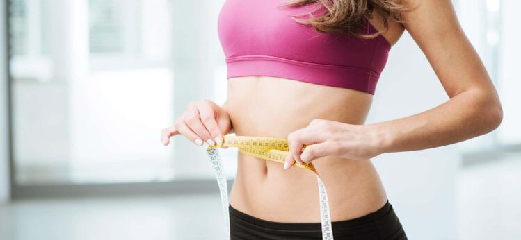 La fille mesure la taille avec un centimètre